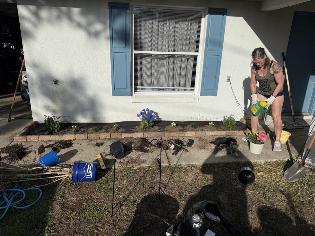D&T crew member watering in new plants along brick-edged foundation bed in Ocala FL