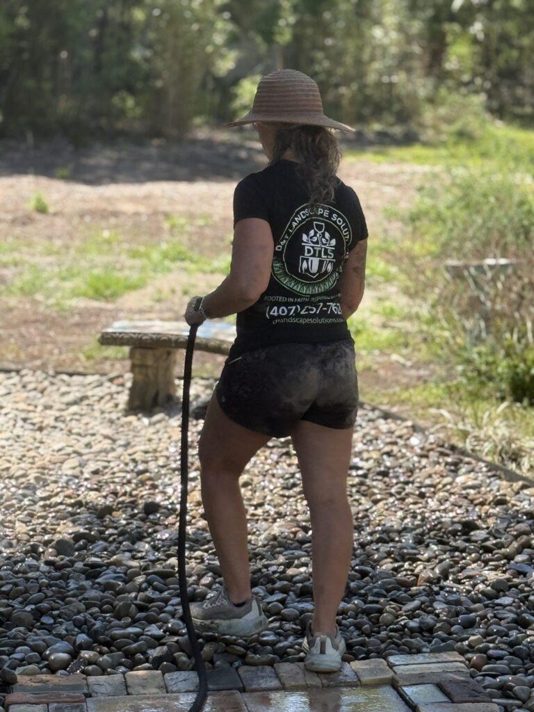 D&T crew member working river rock install with garden hose in Ocala FL