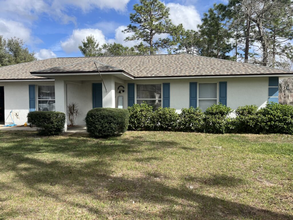 White Ocala FL home with shaped shrubs and well-kept green lawn