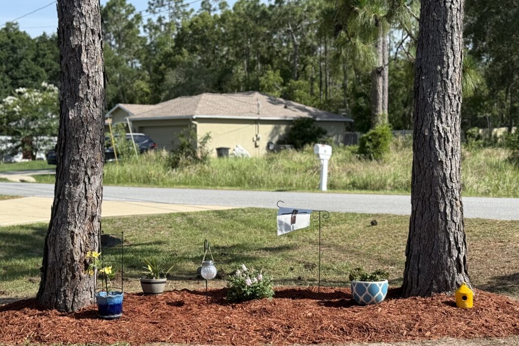 Memorial garden with red mulch in a tree-shaded Ocala FL neighborhood yard