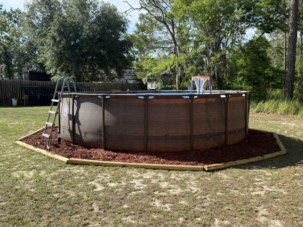 Finished above-ground pool base with red mulch edging in Ocala FL backyard