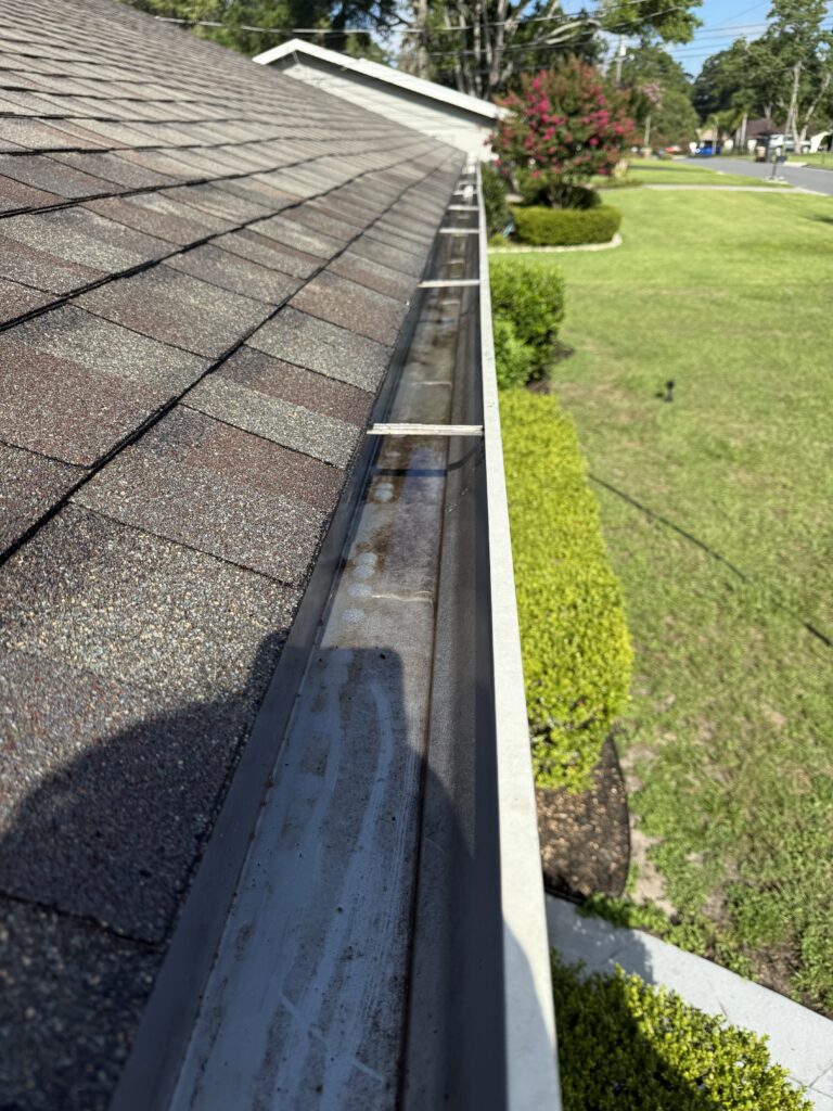 Rain gutter with standing water and debris before cleaning in Ocala FL