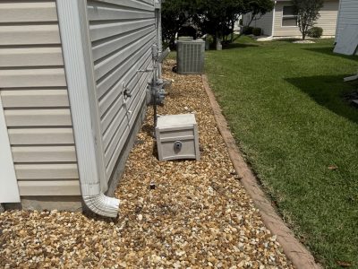 Side utility area with white fence and rock gravel install after cleanup in Ocala FL